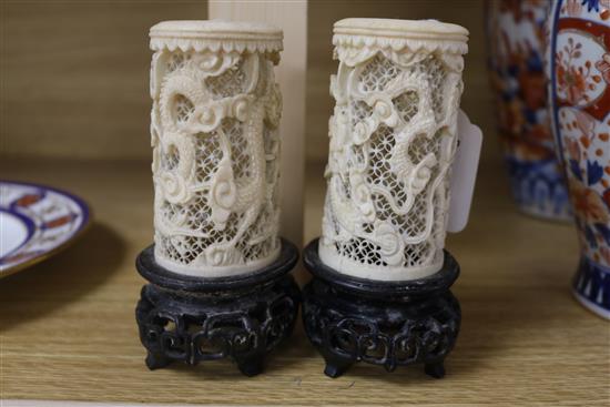 A pair of Chinese carved ivory tusk reticulated vases, carved with dragons among clouds and with carved and pierced hardwood stands